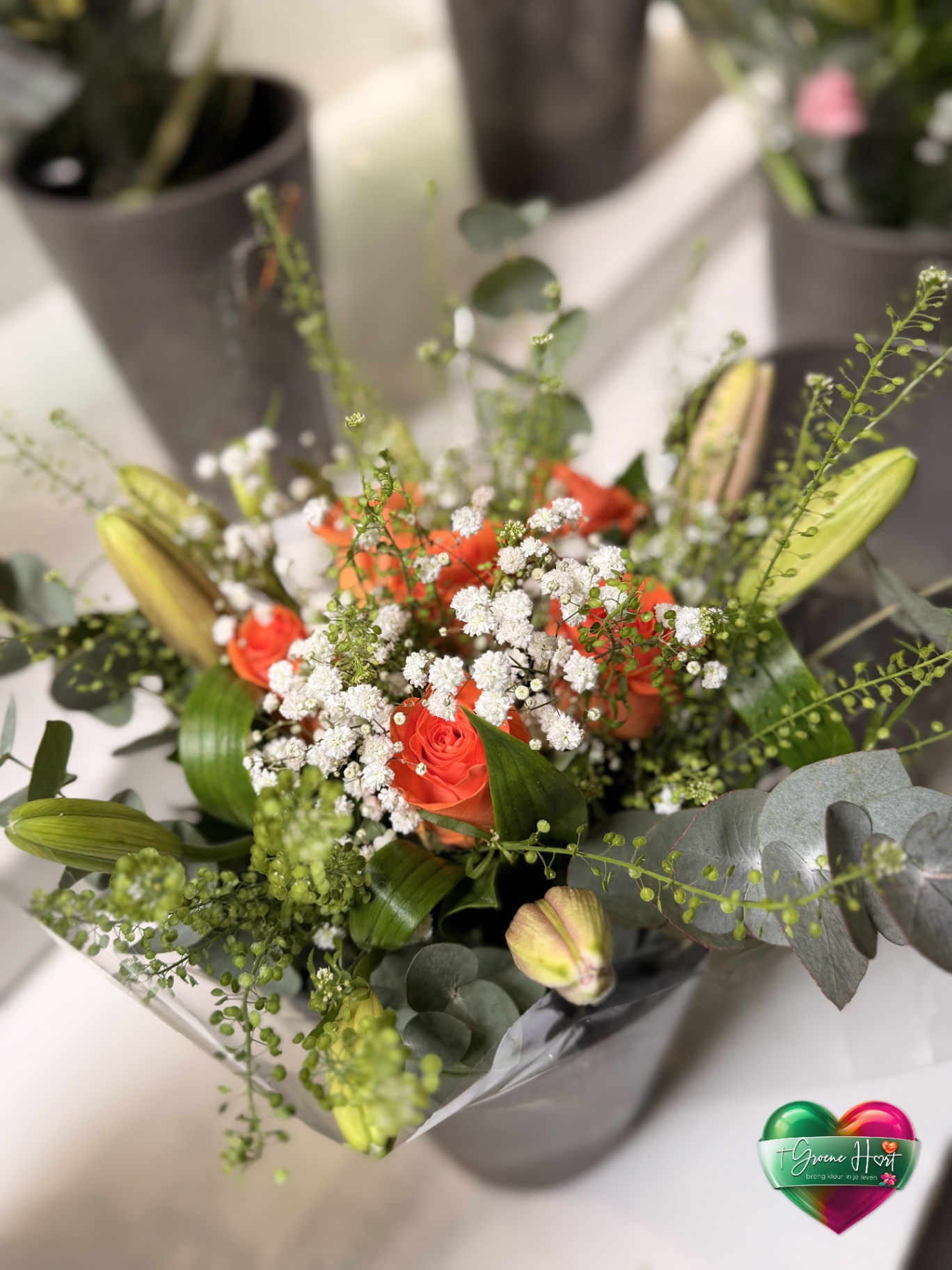 Oranje rozen met gipskruid, lelies en eucalyptus
