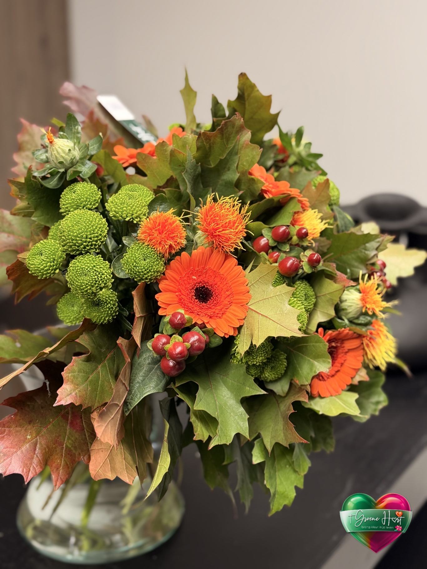 Oranje herfstboeket met groene chrysanten en bessen