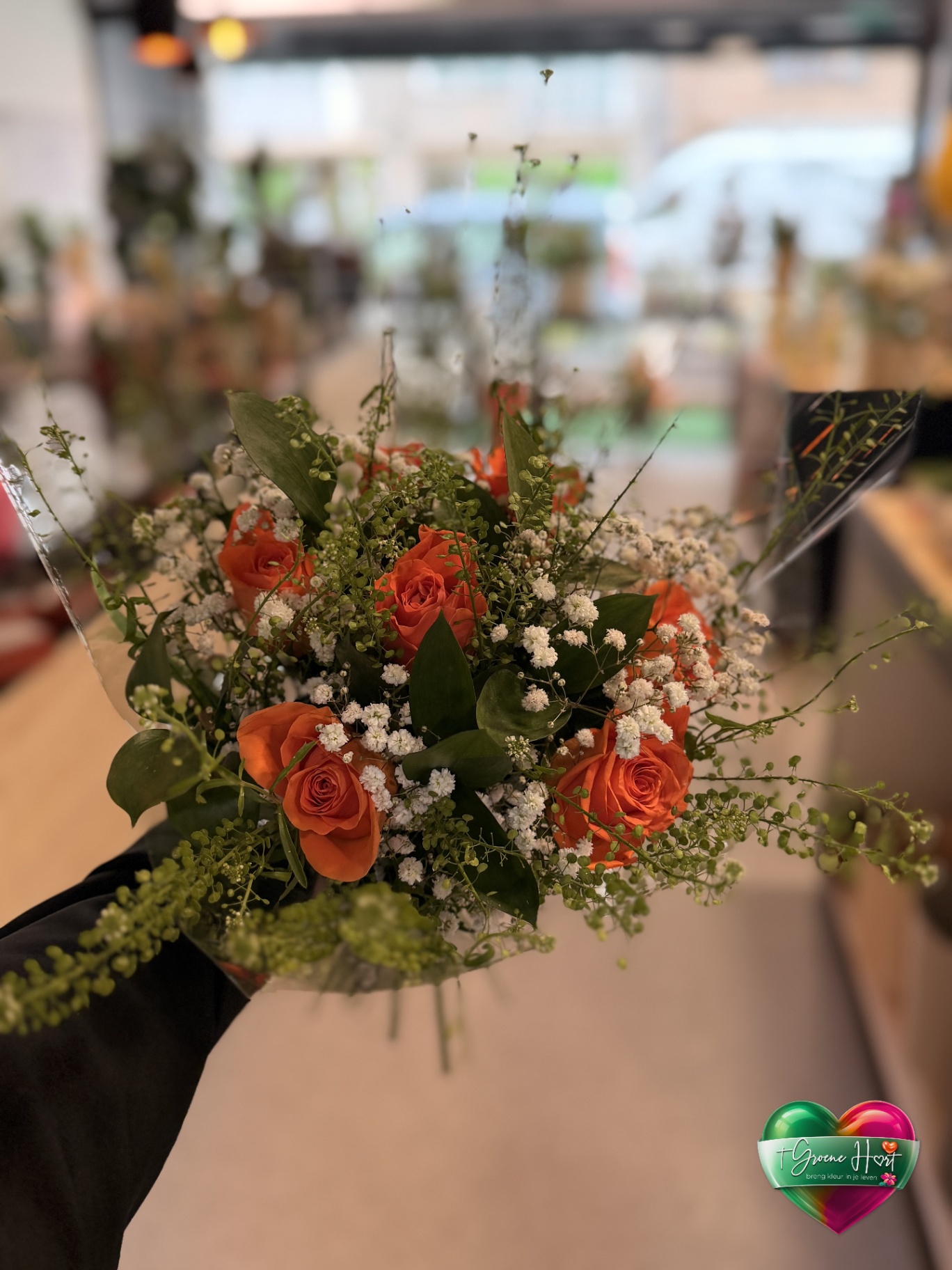 Compact oranje rozenboeket met witte gipskruidaccenten