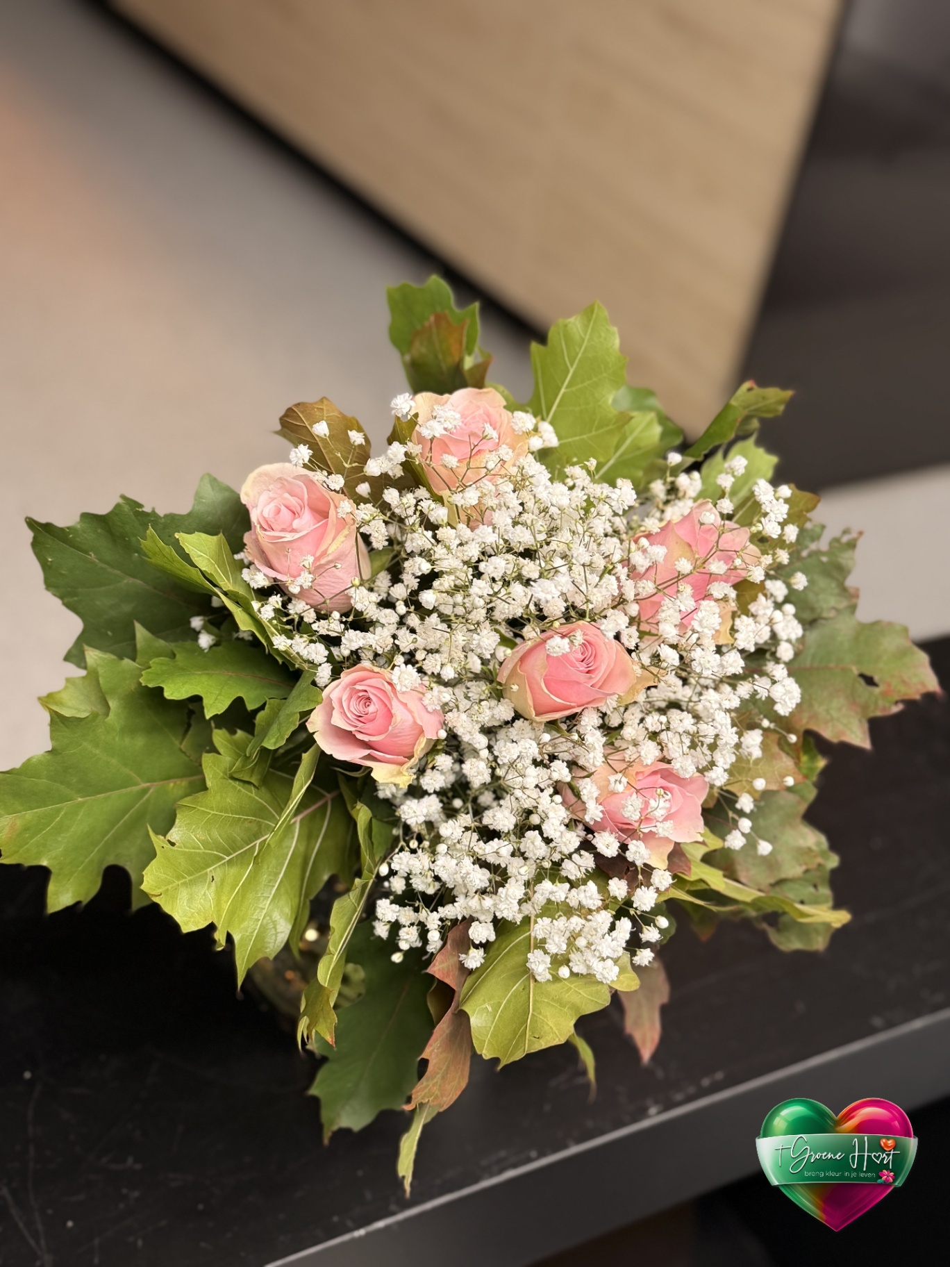 Roze rozen met gipskruid en groene eikenbladeren
