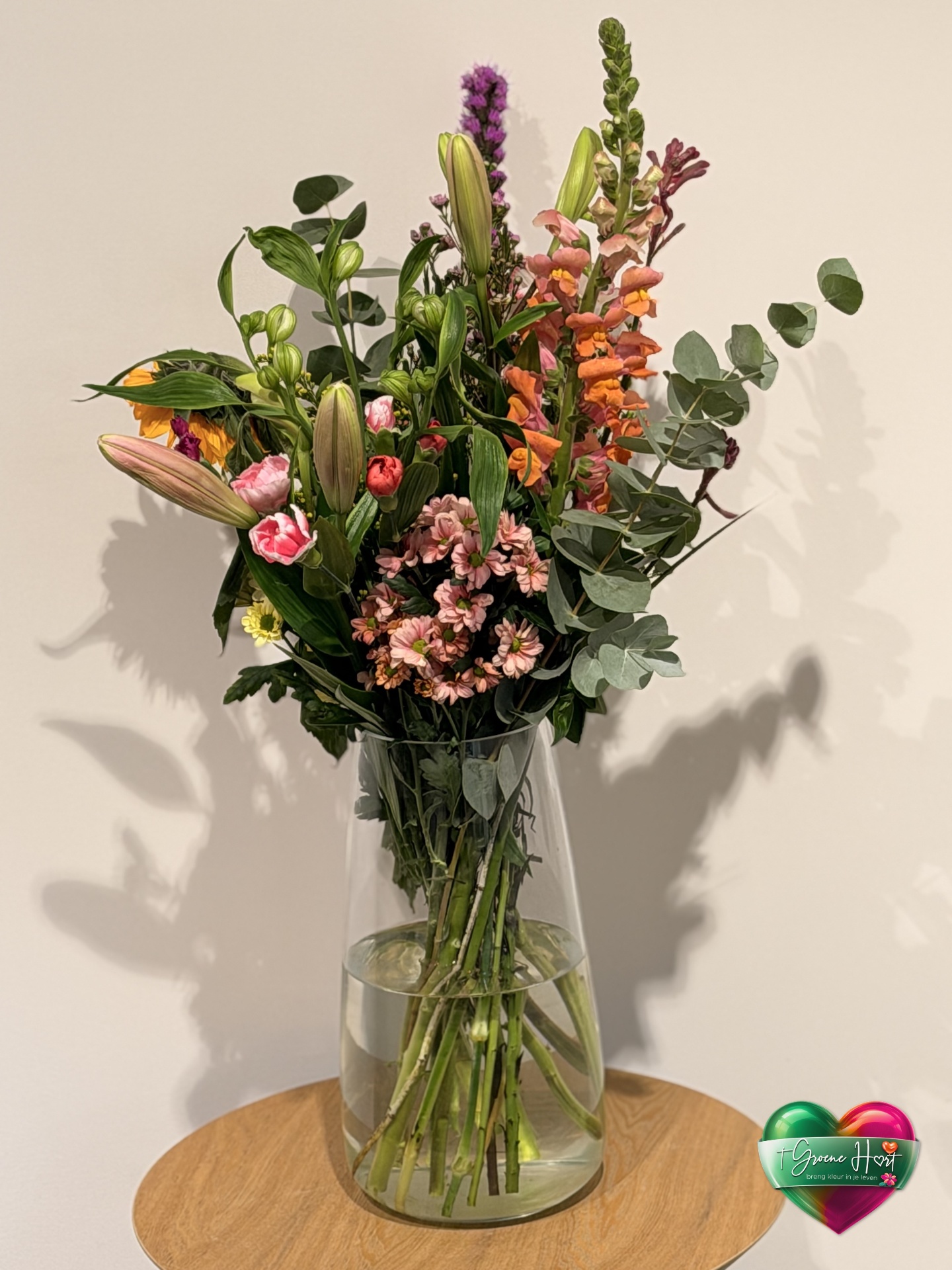 Hoog veldboeket met leeuwenbek, liatris en chrysanten in glazen vaas