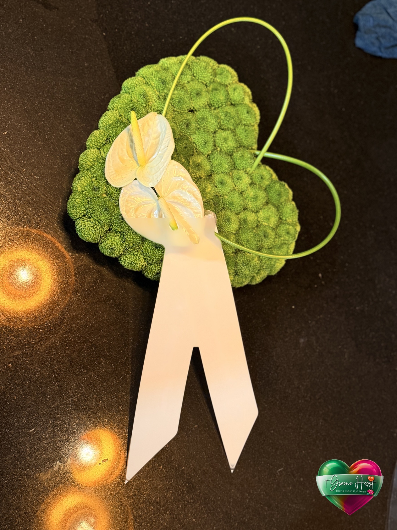 Groen bloemstuk met witte anthurium en lint