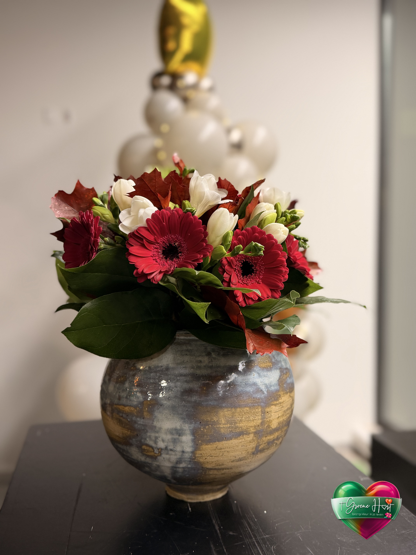 Feestelijk boeket met rode gerbera's en witte fresia's in keramiek vaas