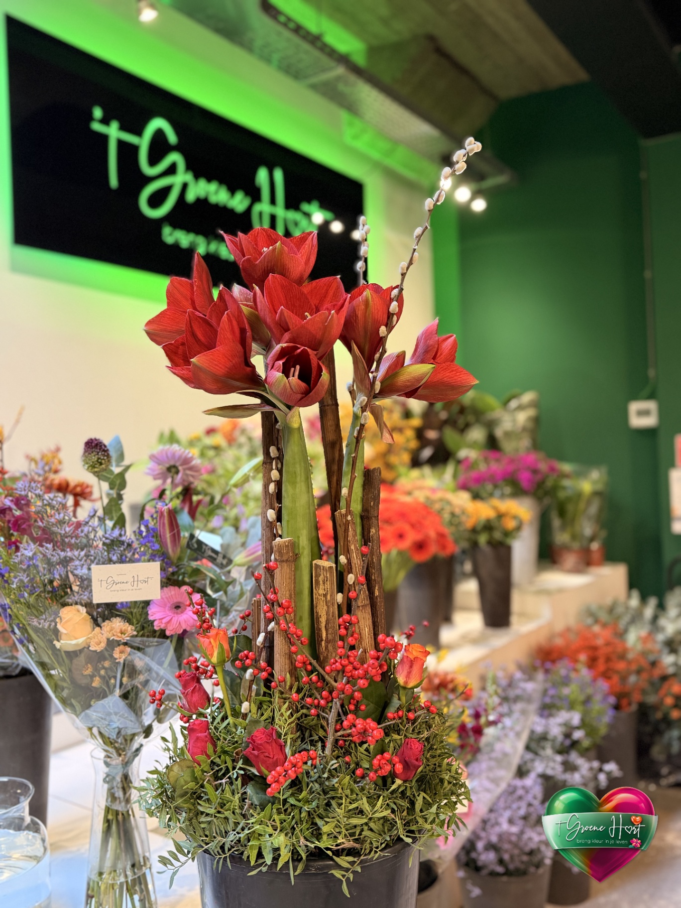 Kerststuk met rode amaryllis, rozen en ilexbessen