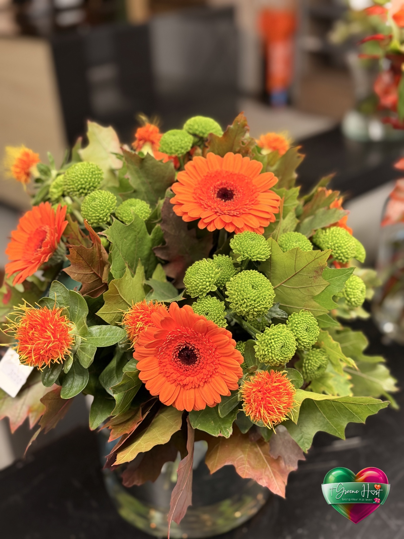 Oranje gerbera's met groene chrysanten en distels